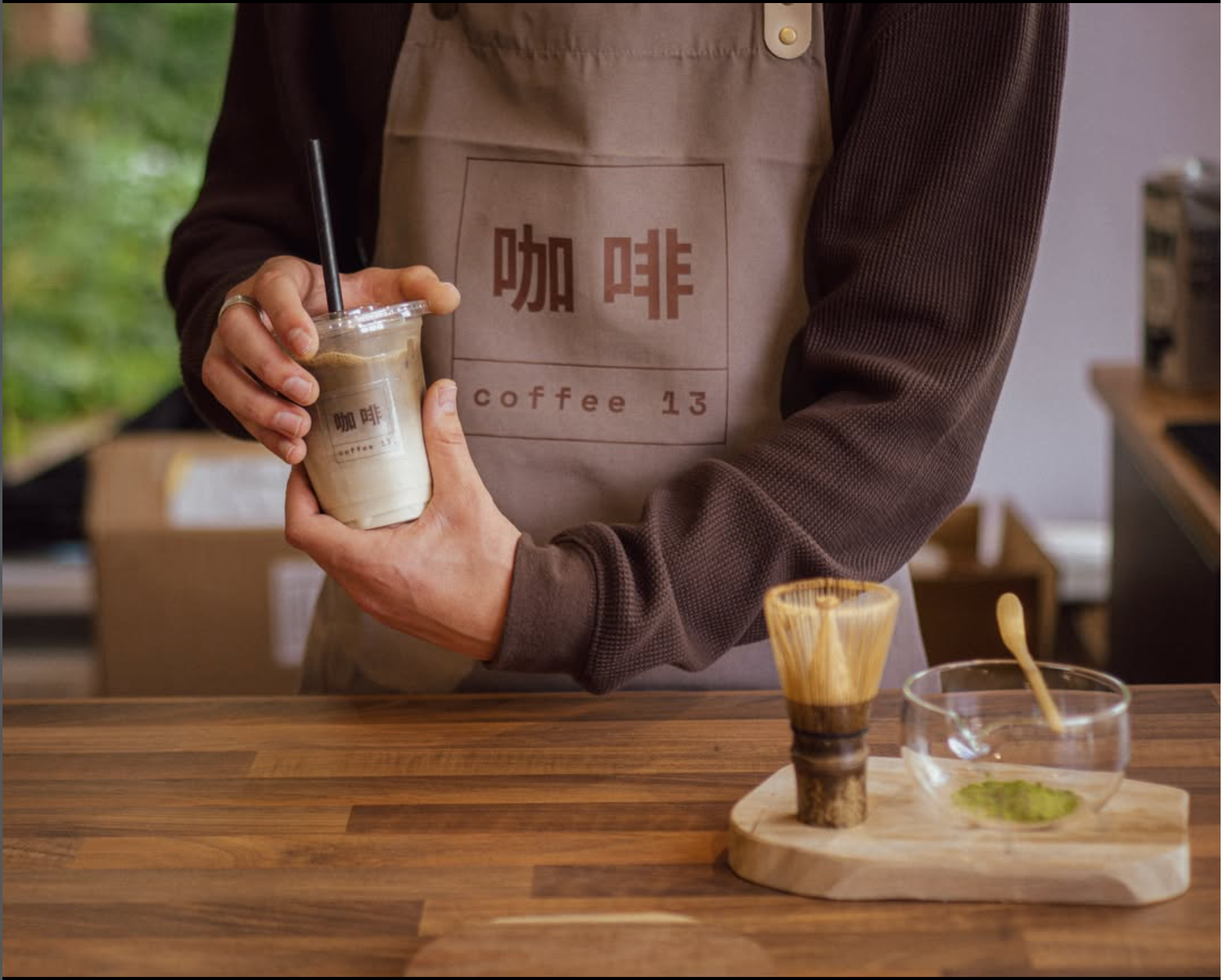Coffee 13 barista holding a freshly made iced drink